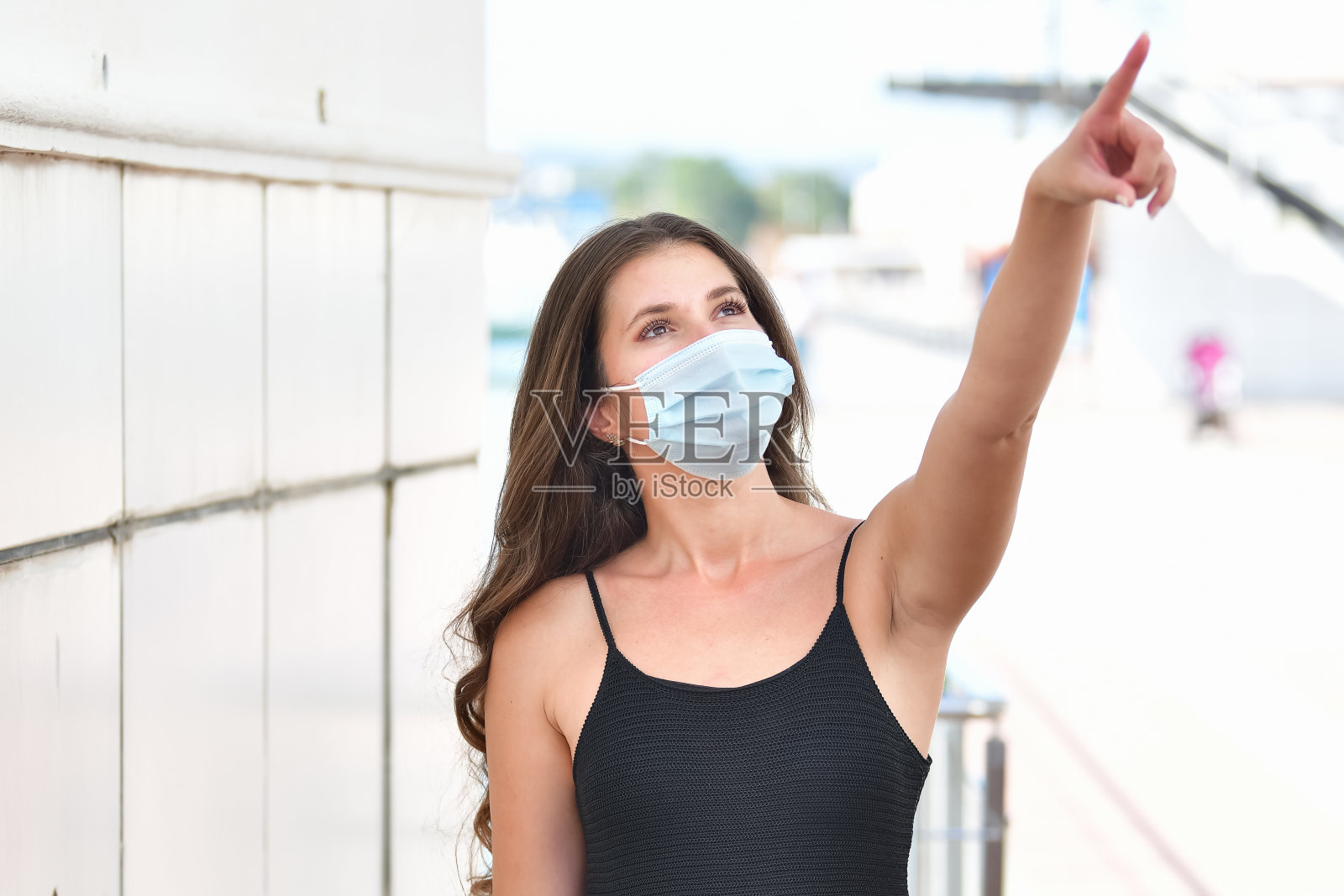 浅焦镜头，一个戴面具的白人女性指向上方照片摄影图片