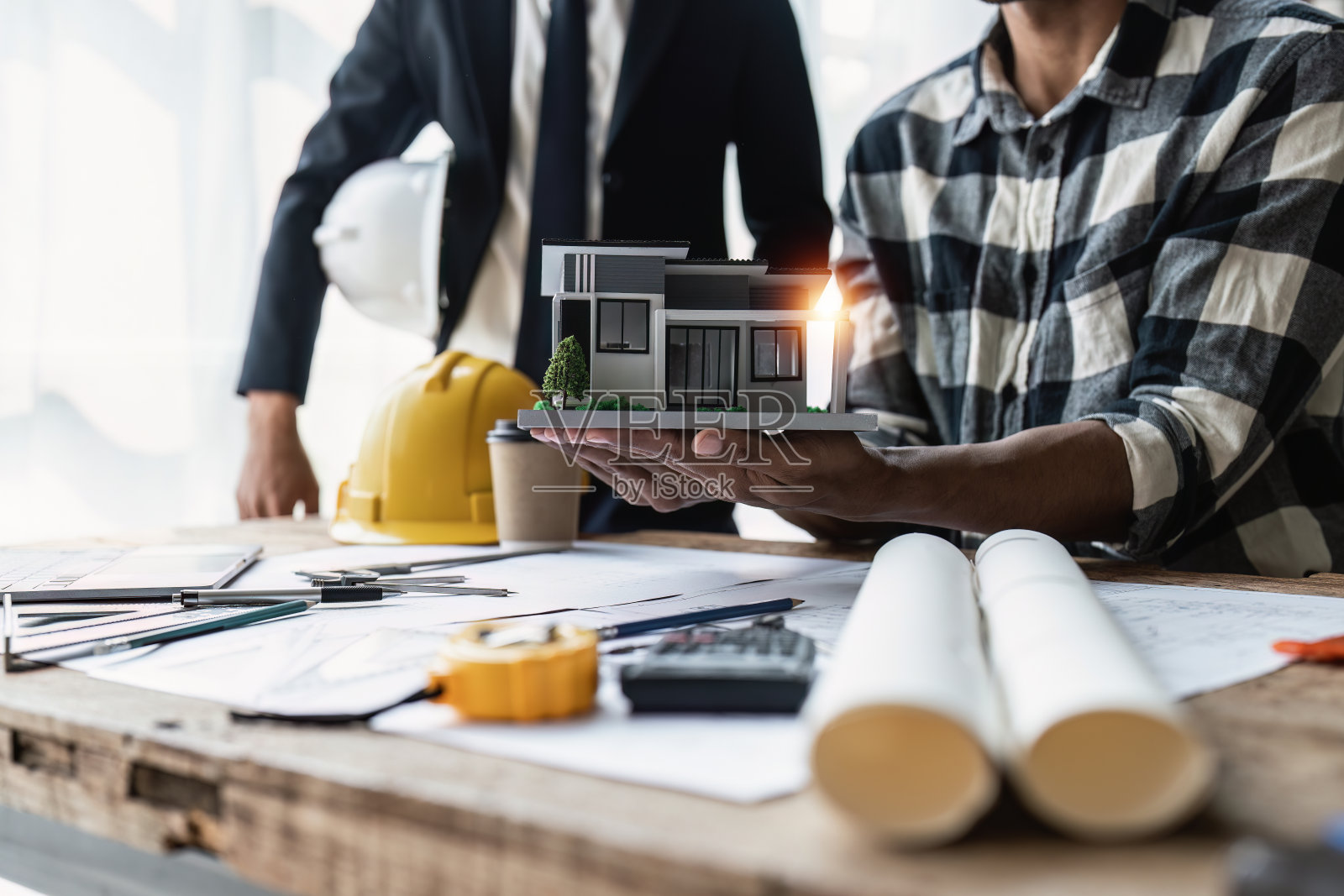 近距离的建筑师团队与房屋模型的建筑计划，工程师草图的建设项目，绿色能源的概念照片摄影图片