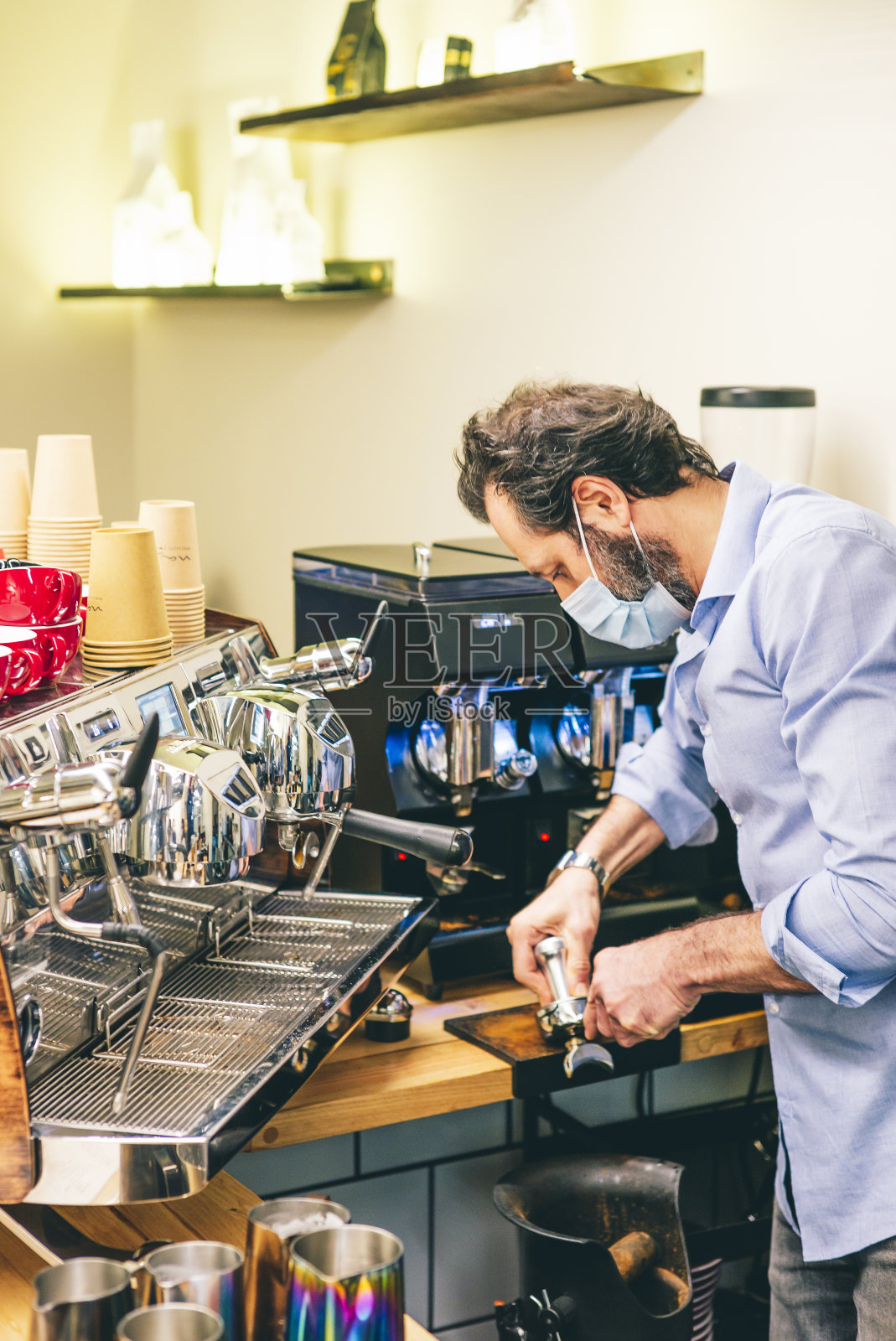 戴着口罩的帅气咖啡师在咖啡店煮咖啡——Covid-19照片摄影图片