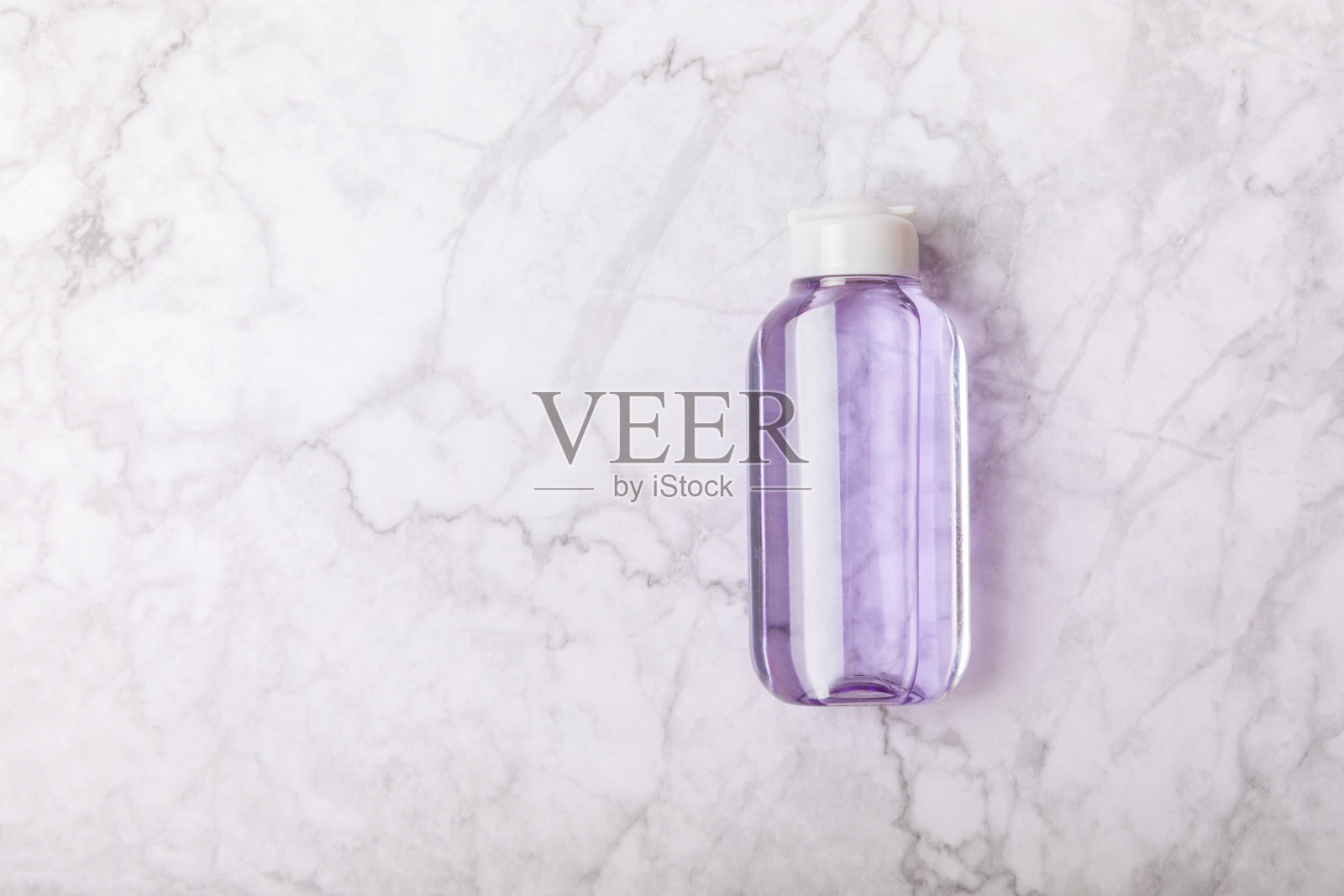 胶束清洁水和棉垫在大理石背景上。洗面奶或卸妆化妆品瓶在浴室。护肤理念。清洁面部彩妆及皮肤皮脂。照片摄影图片