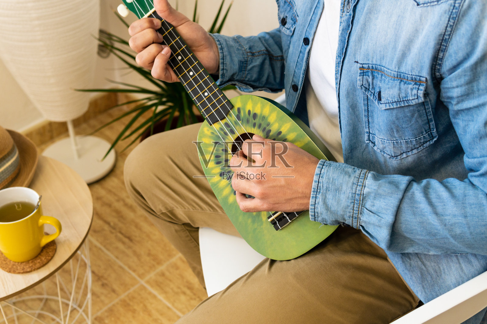 一个面目全非的男人在一个现代化的工作室里弹奏绿色的四弦琴照片摄影图片