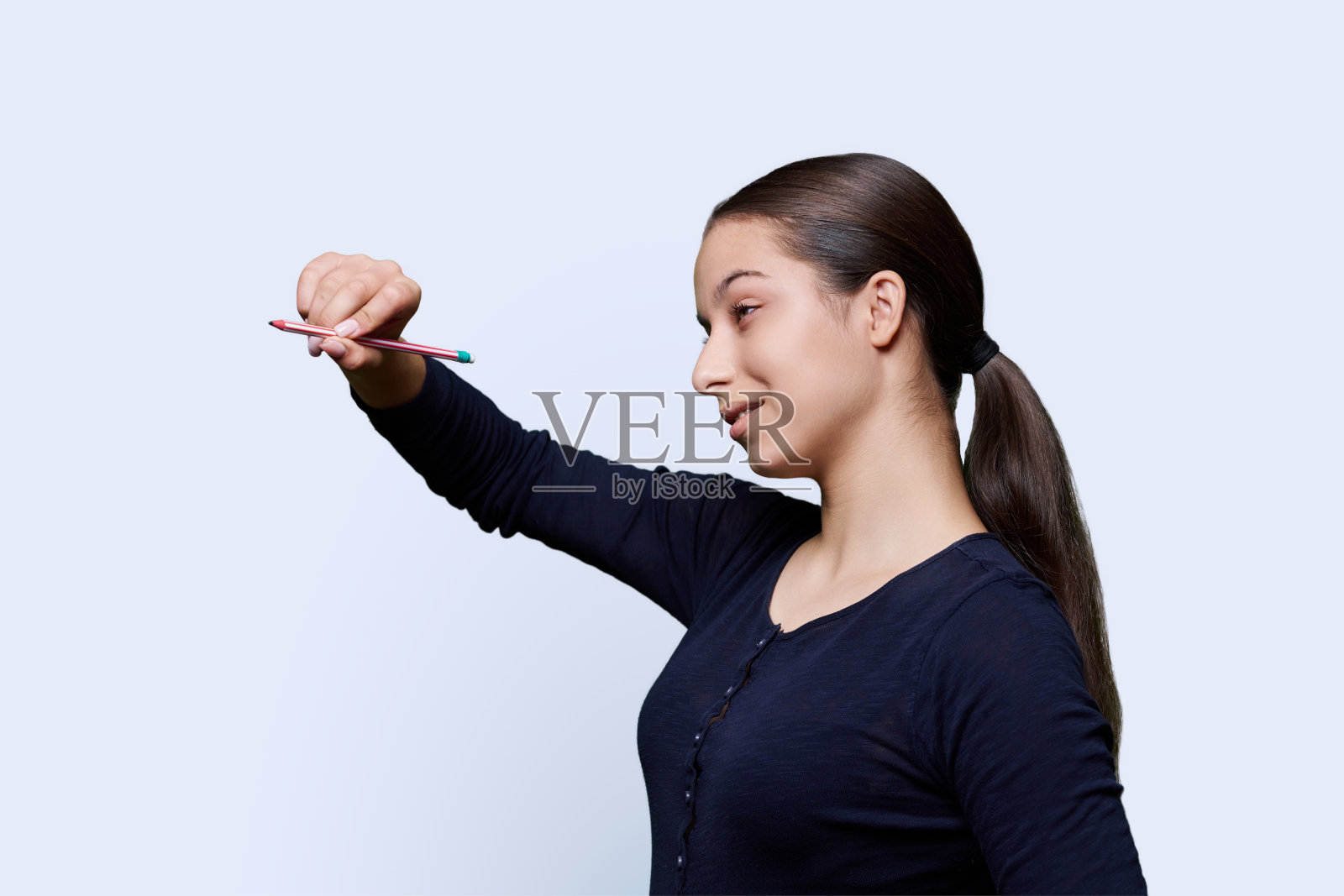 一个十几岁的女孩用铅笔在一个抽象的屏幕上画画照片摄影图片