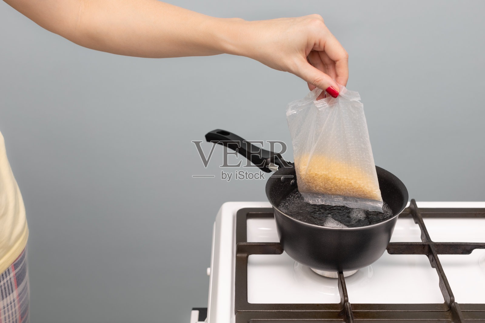 厨房里的一个女人把一袋米浸入水中照片摄影图片