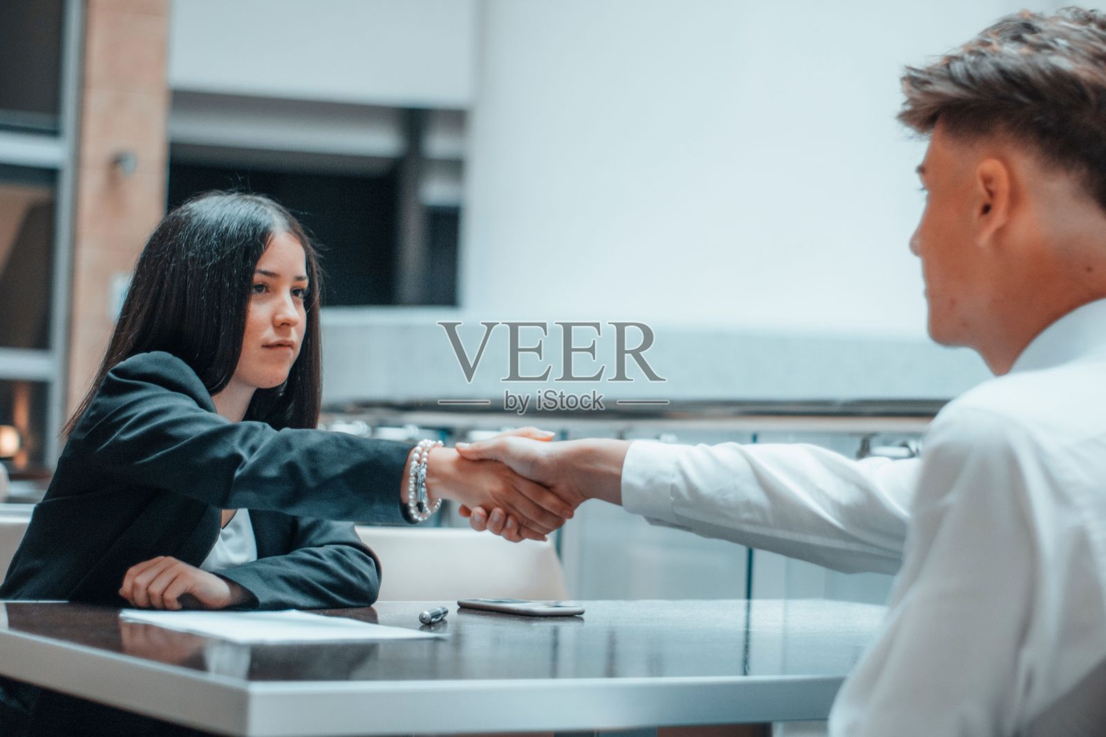 年轻女子在她的办公室与她的客户握手照片摄影图片