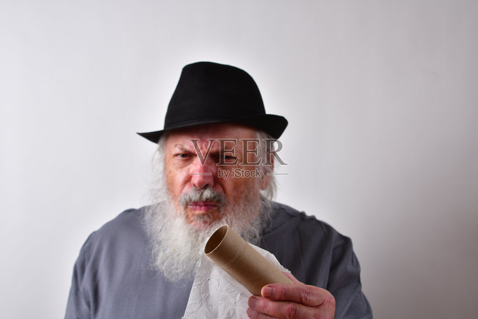 一个暴躁的美国老男人在白色的墙壁背景下对卫生纸用完了的反应照片摄影图片