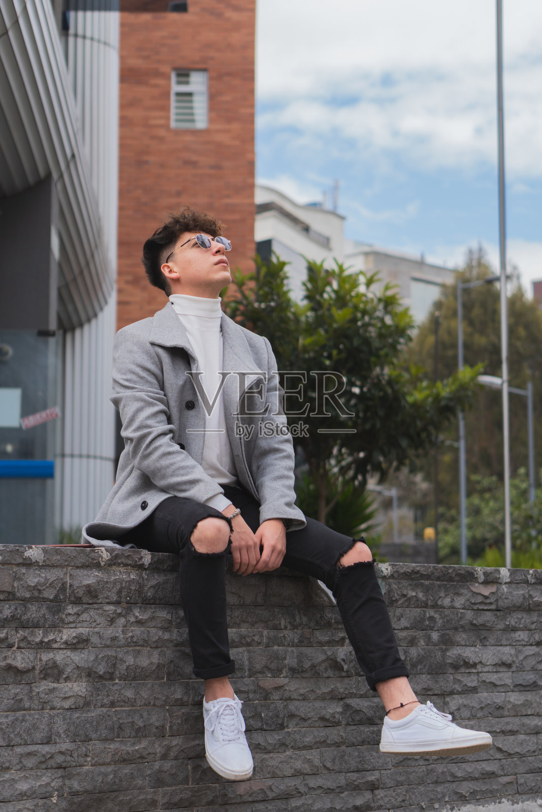 年轻的拉丁裔商人戴着墨镜坐在办公楼前照片摄影图片