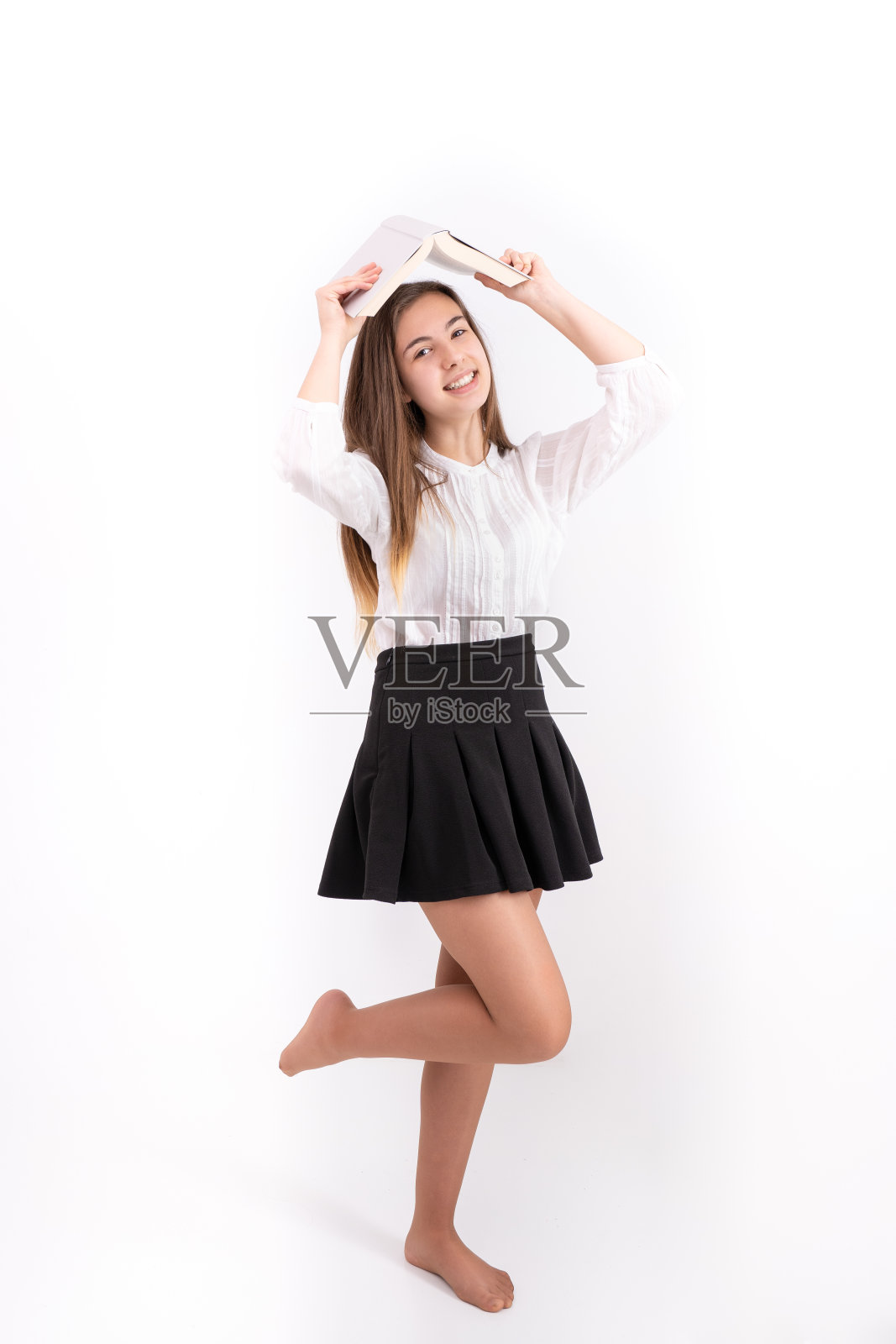 一个美丽的年轻女士拿着一本书，穿着黑色裙子和白色衬衫的垂直镜头照片摄影图片