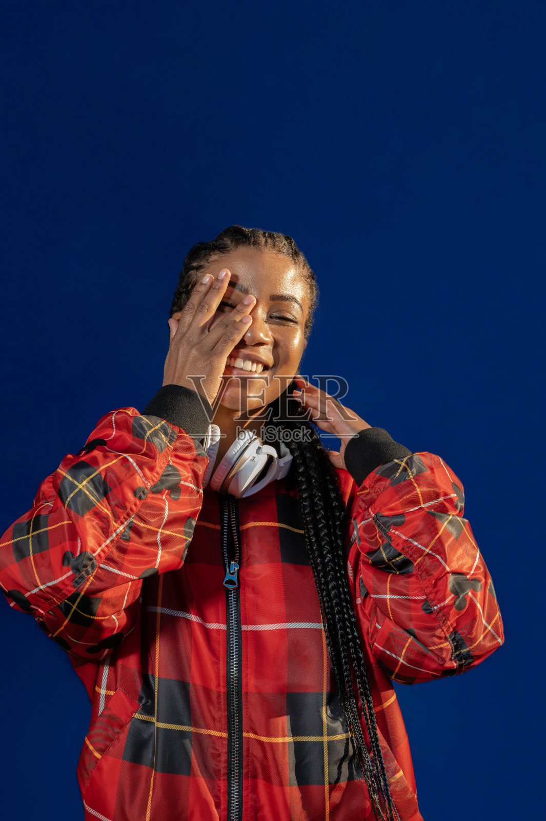 一个年轻的非洲裔美国女性在蓝色背景上快乐地微笑的垂直肖像照片摄影图片