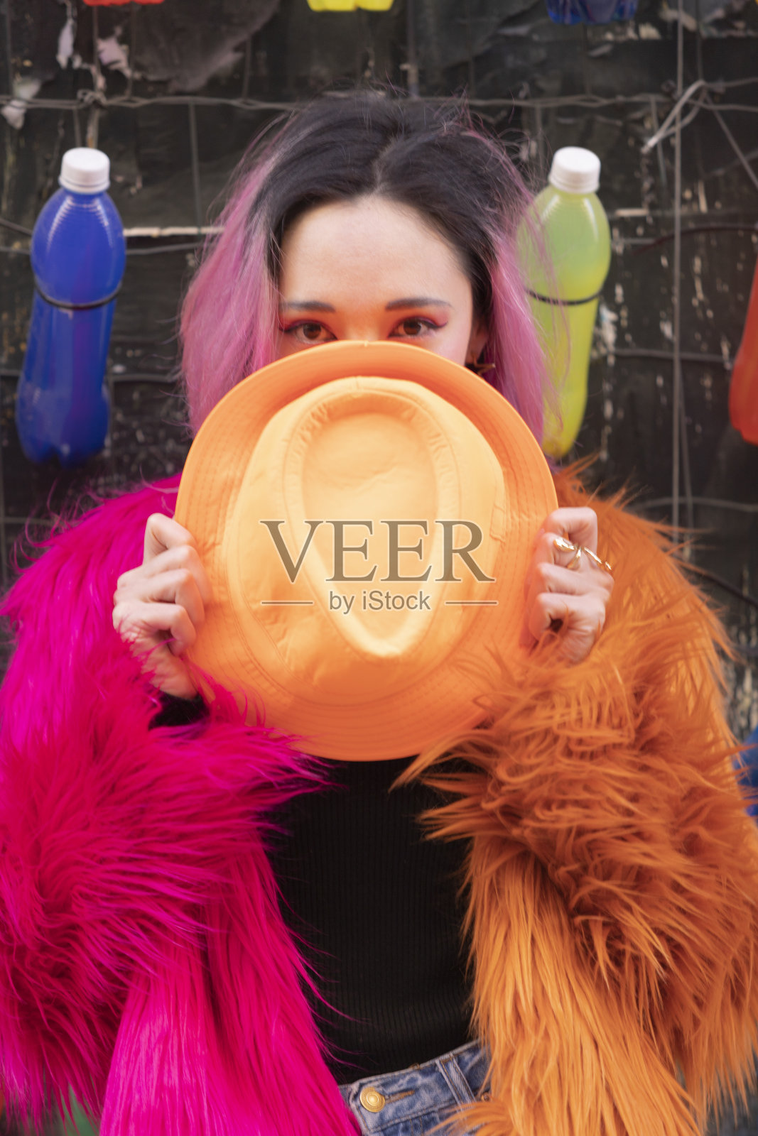 浅焦点的西班牙女子与粉红色的头发穿着蓬松的夹克，拿着一顶软呢帽照片摄影图片