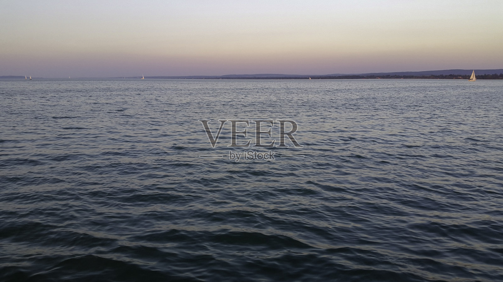 粉红色的天空下海洋涟漪的宁静景色照片摄影图片