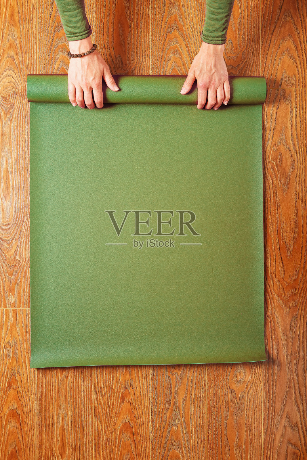 一位女士在瑜伽课后收集绿色垫子照片摄影图片