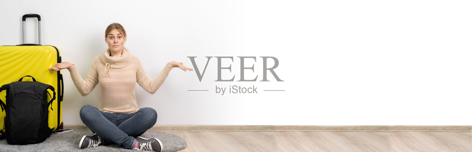 在白色背景上，穿着休闲服装、背着旅行箱和背包的女游客以怀疑的姿态耸着肩膀。境外旅客旅行。飞行旅程照片摄影图片