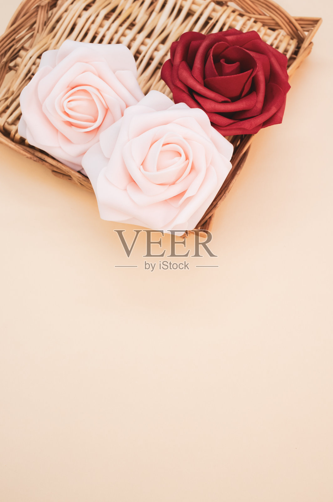 垂直拍摄的柳条托盘上有红色和粉色的玫瑰，浅色背景上有文字空间照片摄影图片