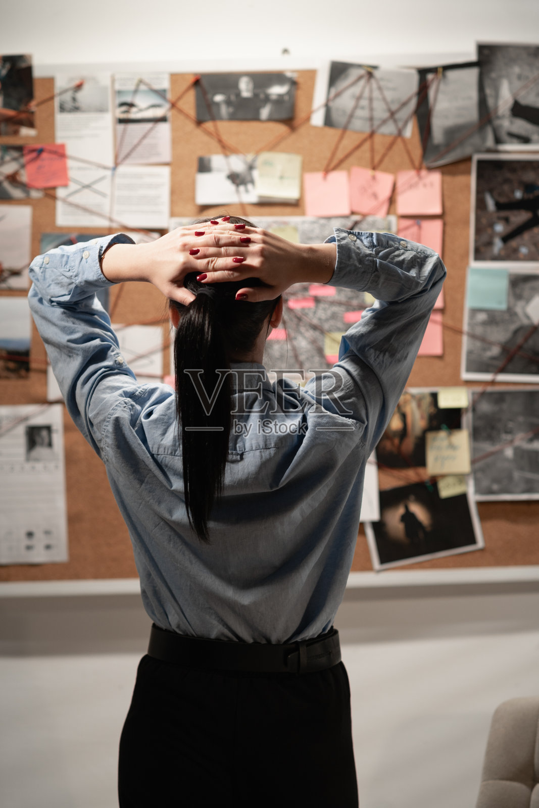 女私家侦探或侦探正在看犯罪调查板，背影照片摄影图片