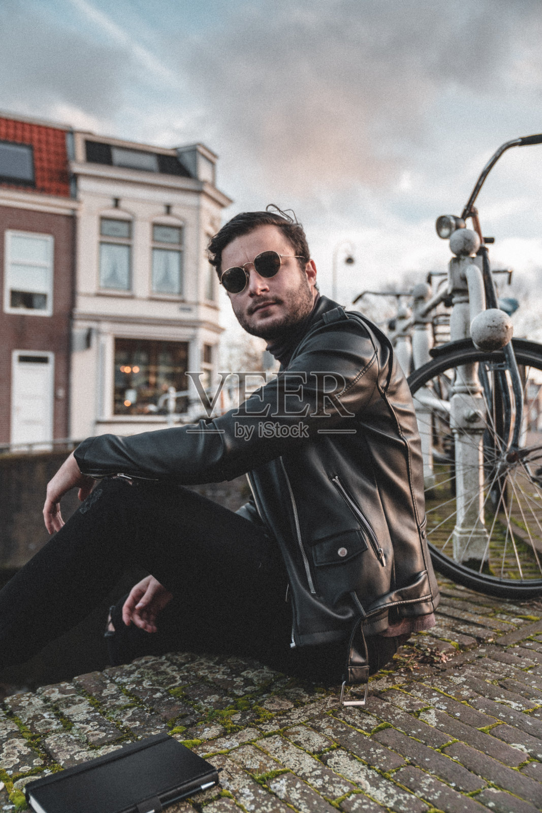 穿着夹克，戴着墨镜的时髦年轻人走在街上照片摄影图片