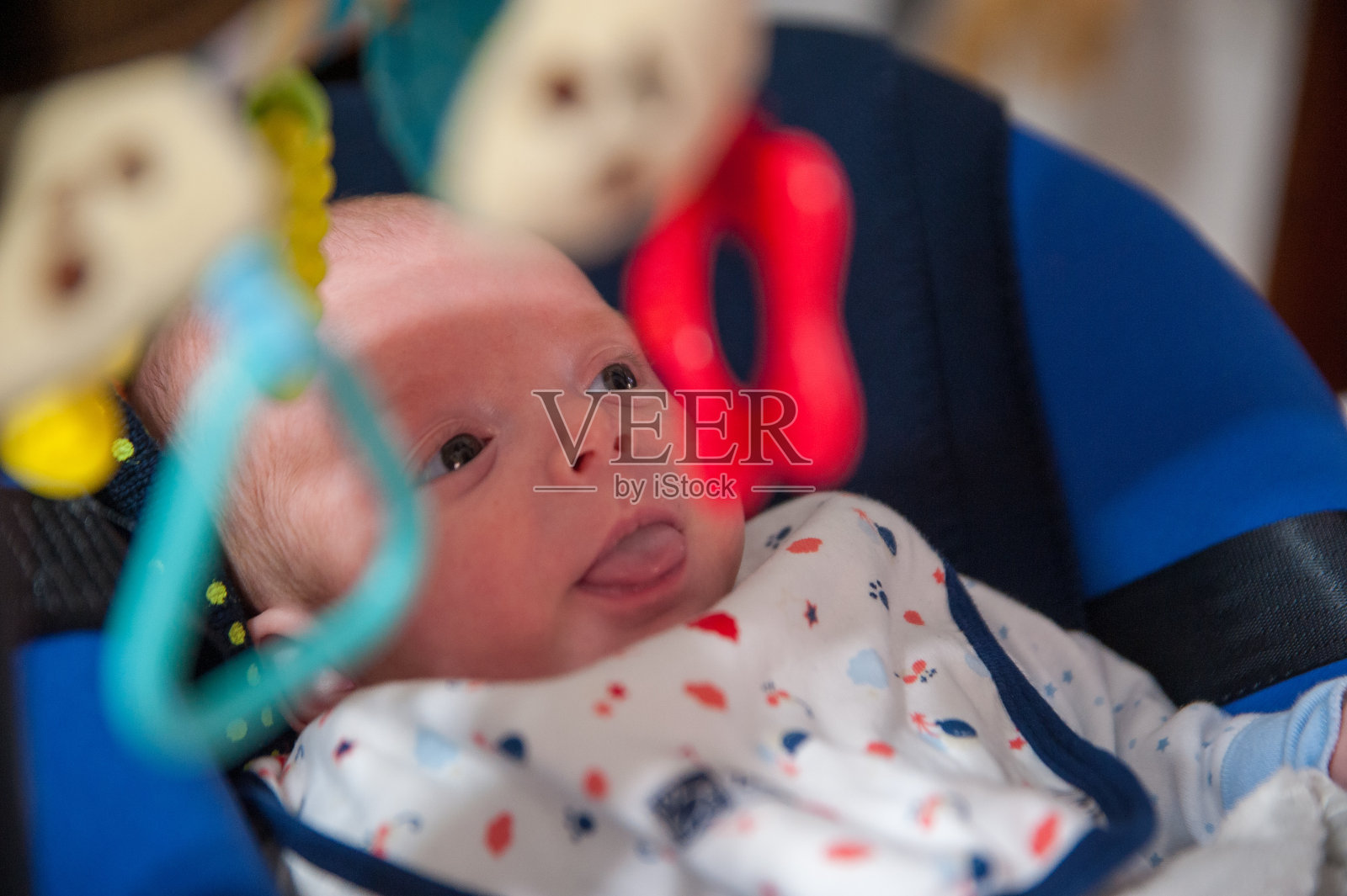 特写镜头:一个可爱的小男孩坐在摇椅上看着悬挂的玩具照片摄影图片