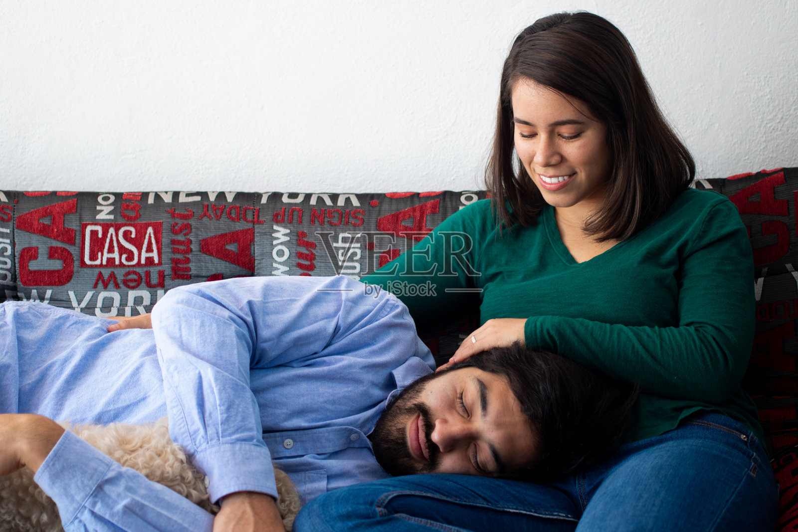 一个西班牙人睡在沙发上一个快乐的年轻拉丁人的腿上照片摄影图片