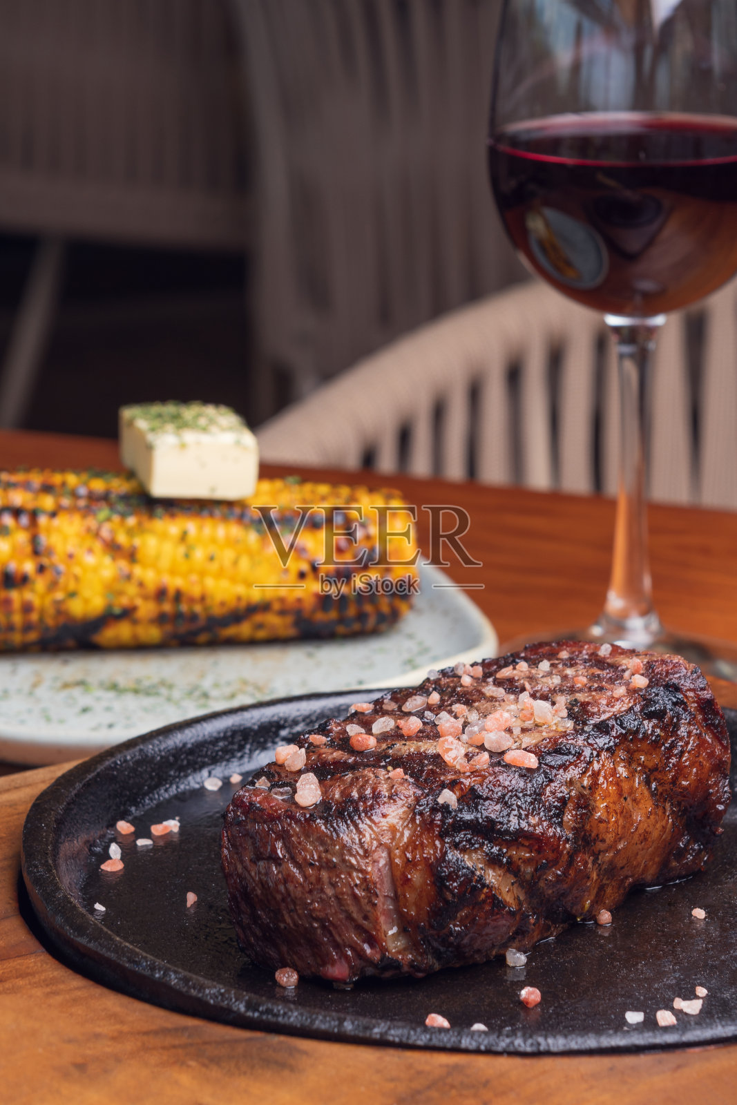 特写镜头烤牛排和装饰黄玉米在木桌上照片摄影图片