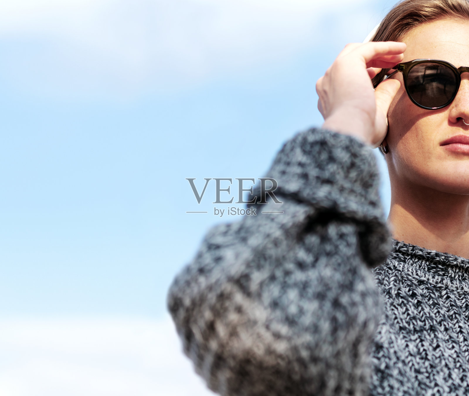 裁剪人像时尚的短发女人太阳镜穿着毛衣站在蓝天。照片摄影图片