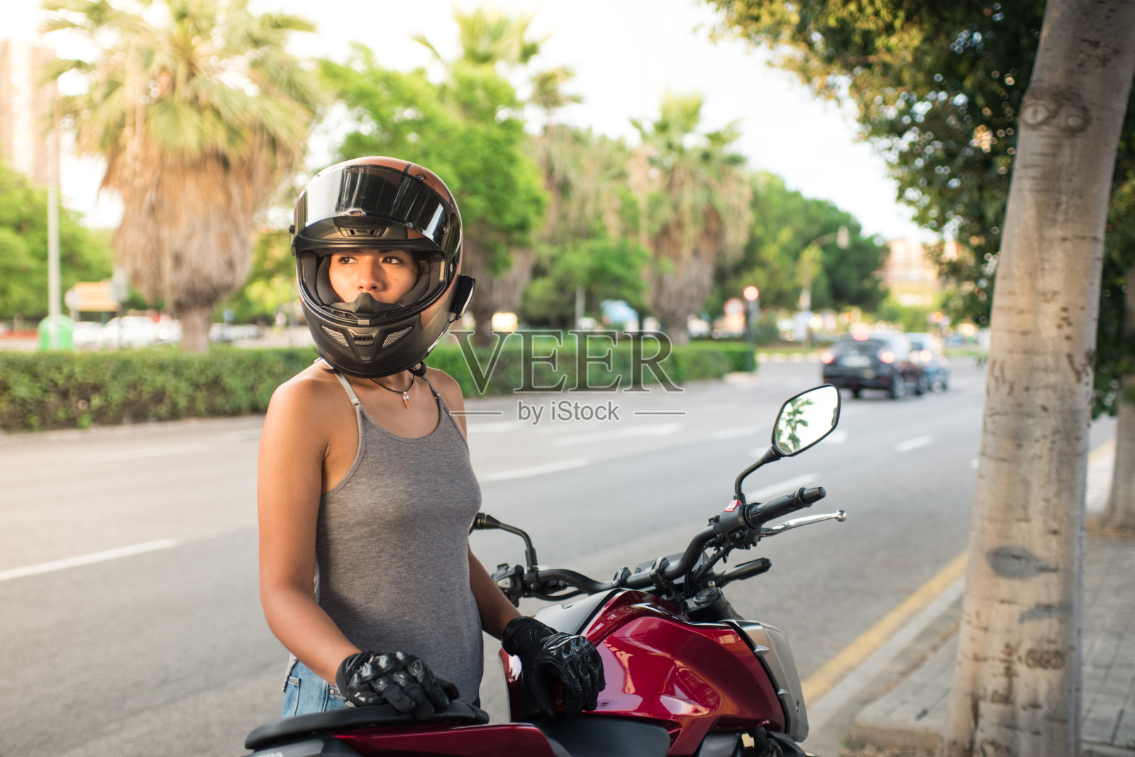 戴着头盔的年轻女子准备在户外骑上一辆现代摩托车照片摄影图片