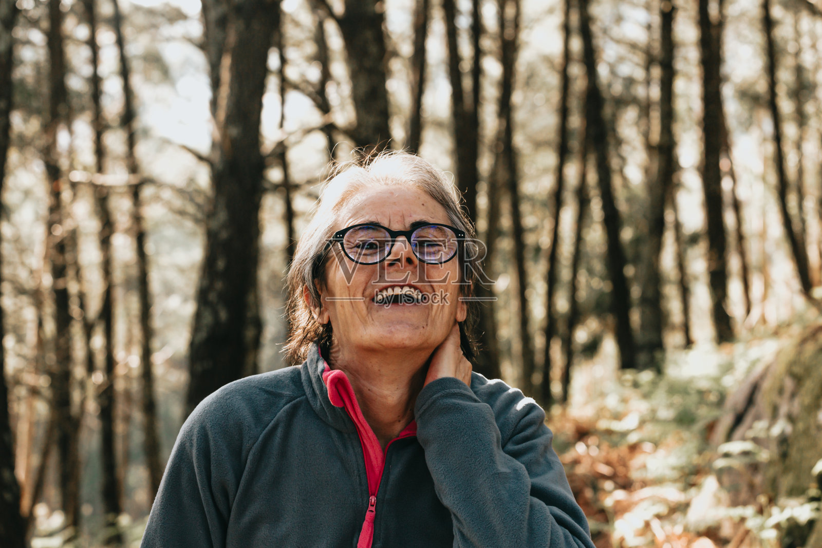 一个白人妇女在森林里笑的特写镜头，阳光下的树木剪影照片摄影图片