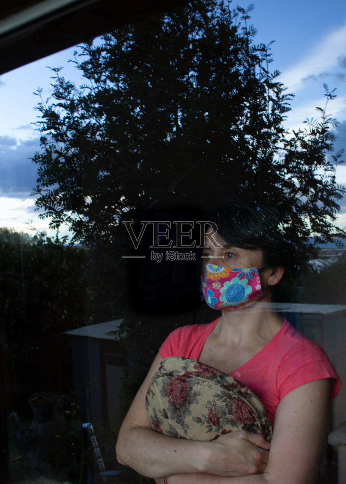 疫情隔离期间戴着口罩站在窗边的悲伤白人女性照片摄影图片