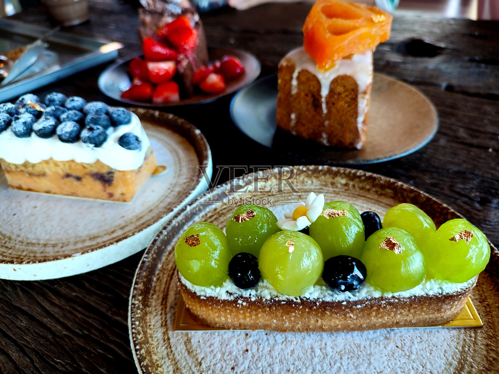 桌上有几种水果蛋糕，重点介绍了Shine Muscat葡萄蛋糕。照片摄影图片
