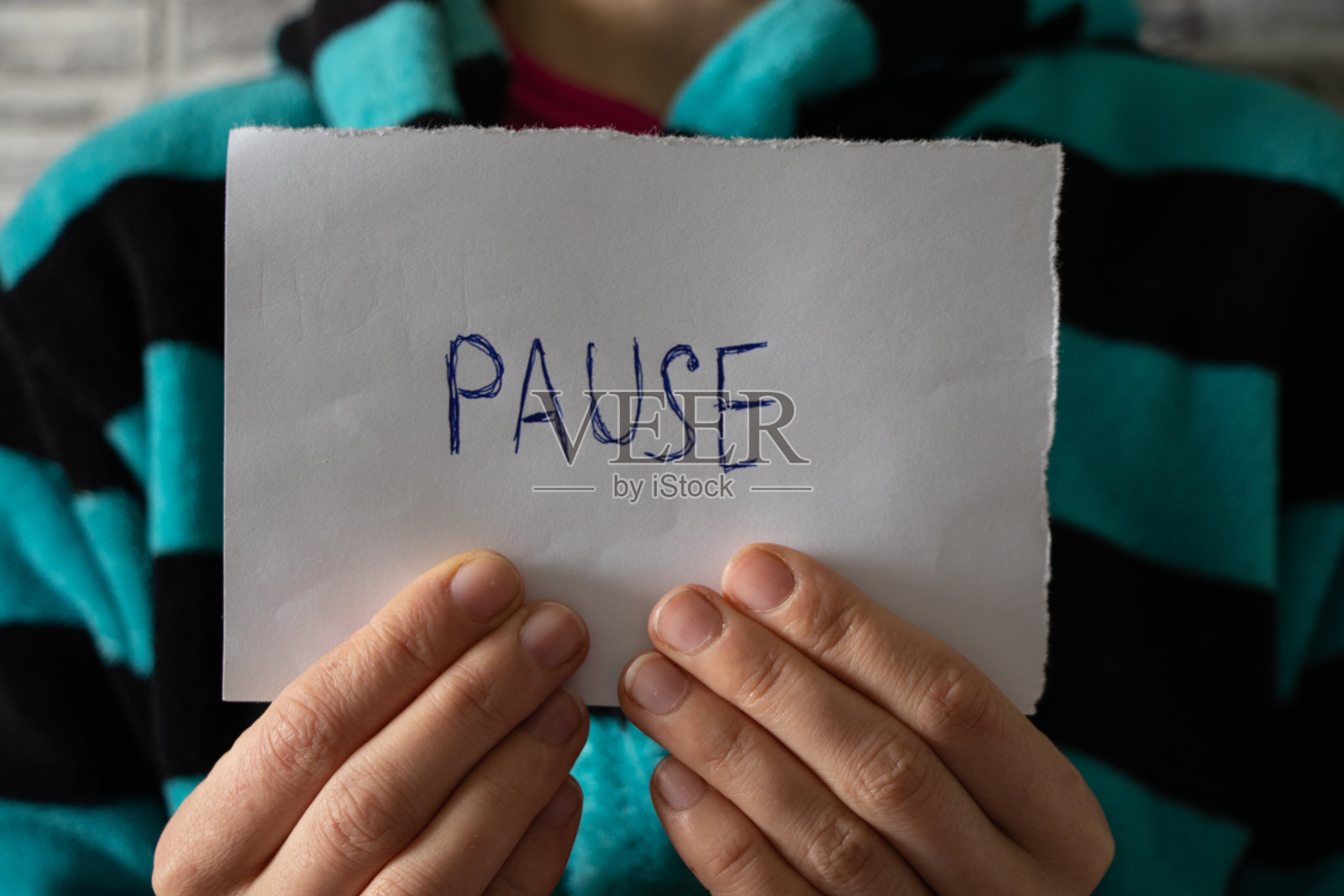 “暂停”这个词写在被隔离的女孩手里拿着的一张纸上照片摄影图片