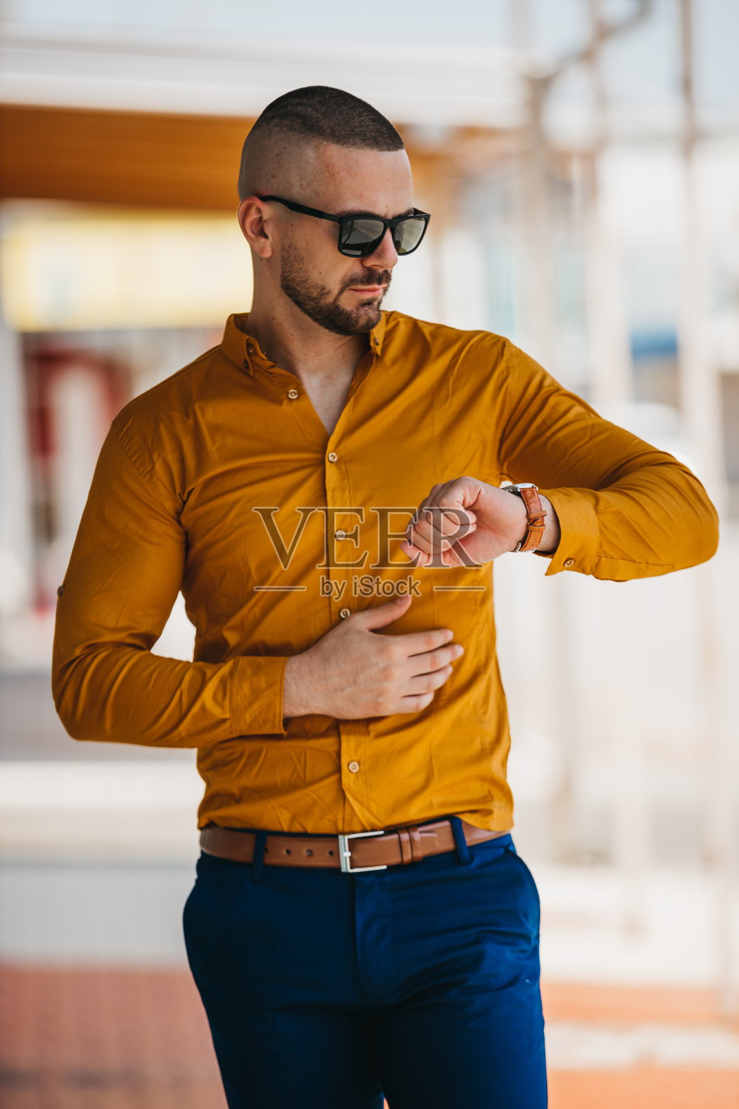 酷帅的白人男子穿着优雅的芥末衬衫和太阳镜摆出户外照片摄影图片