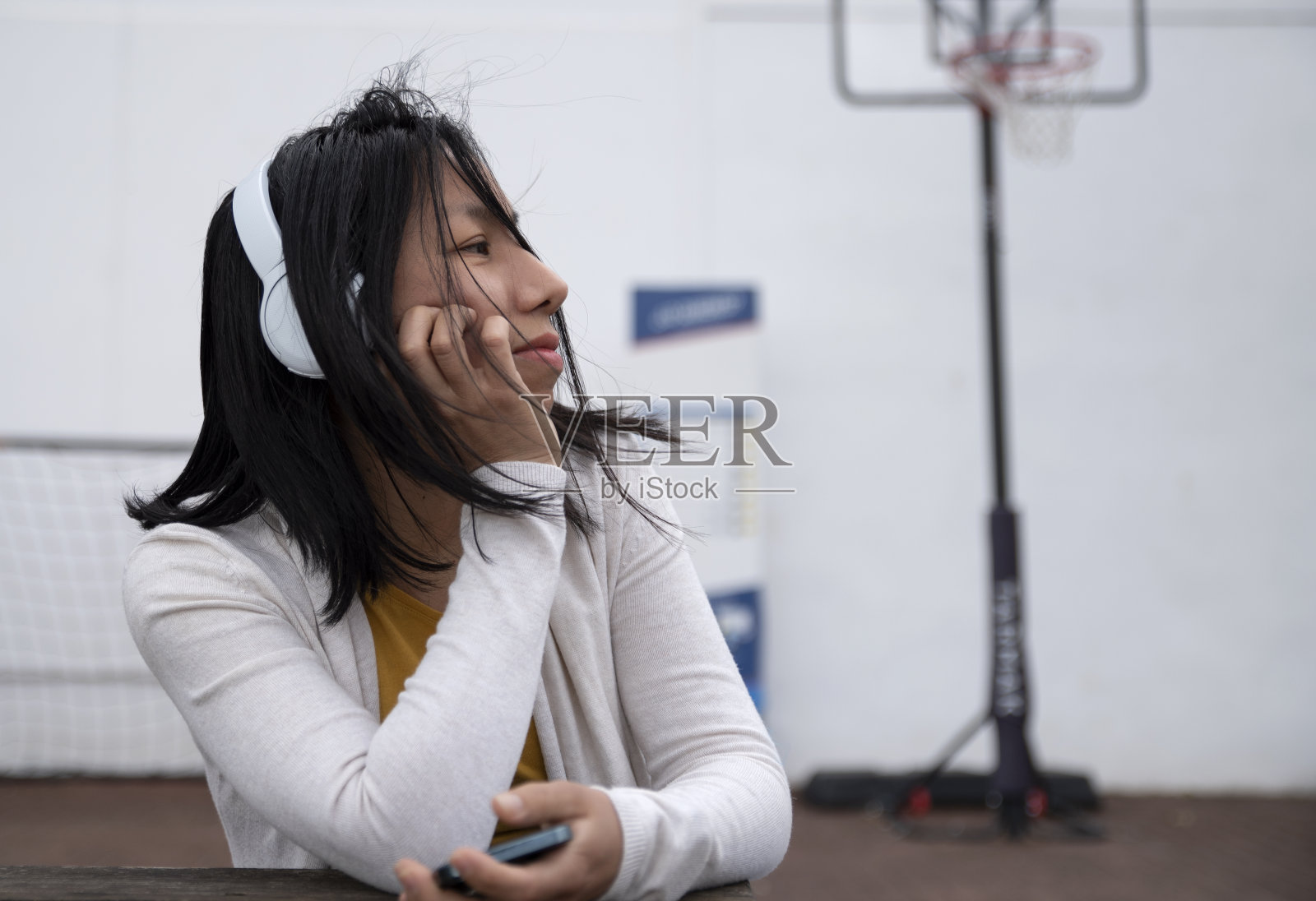 美丽的西班牙女子戴着耳机在户外拿着手机照片摄影图片