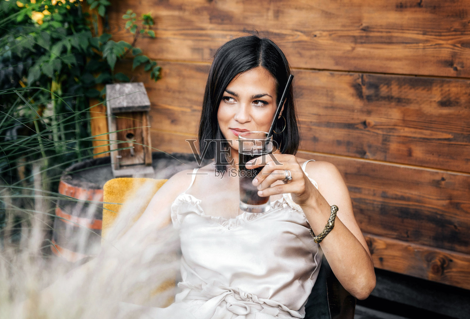 年轻漂亮的女人坐在酒吧里，拿着饮料。照片摄影图片