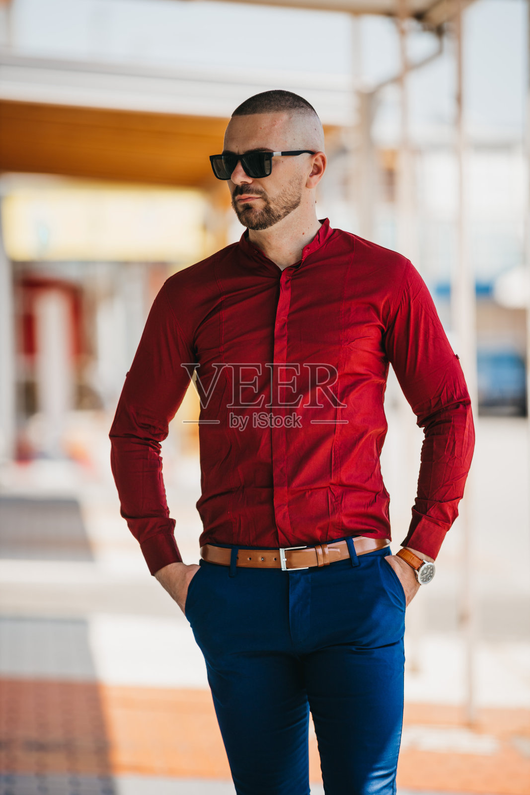 帅气的白人男子穿着优雅的红色衬衫，戴着太阳镜在户外摆姿势照片摄影图片