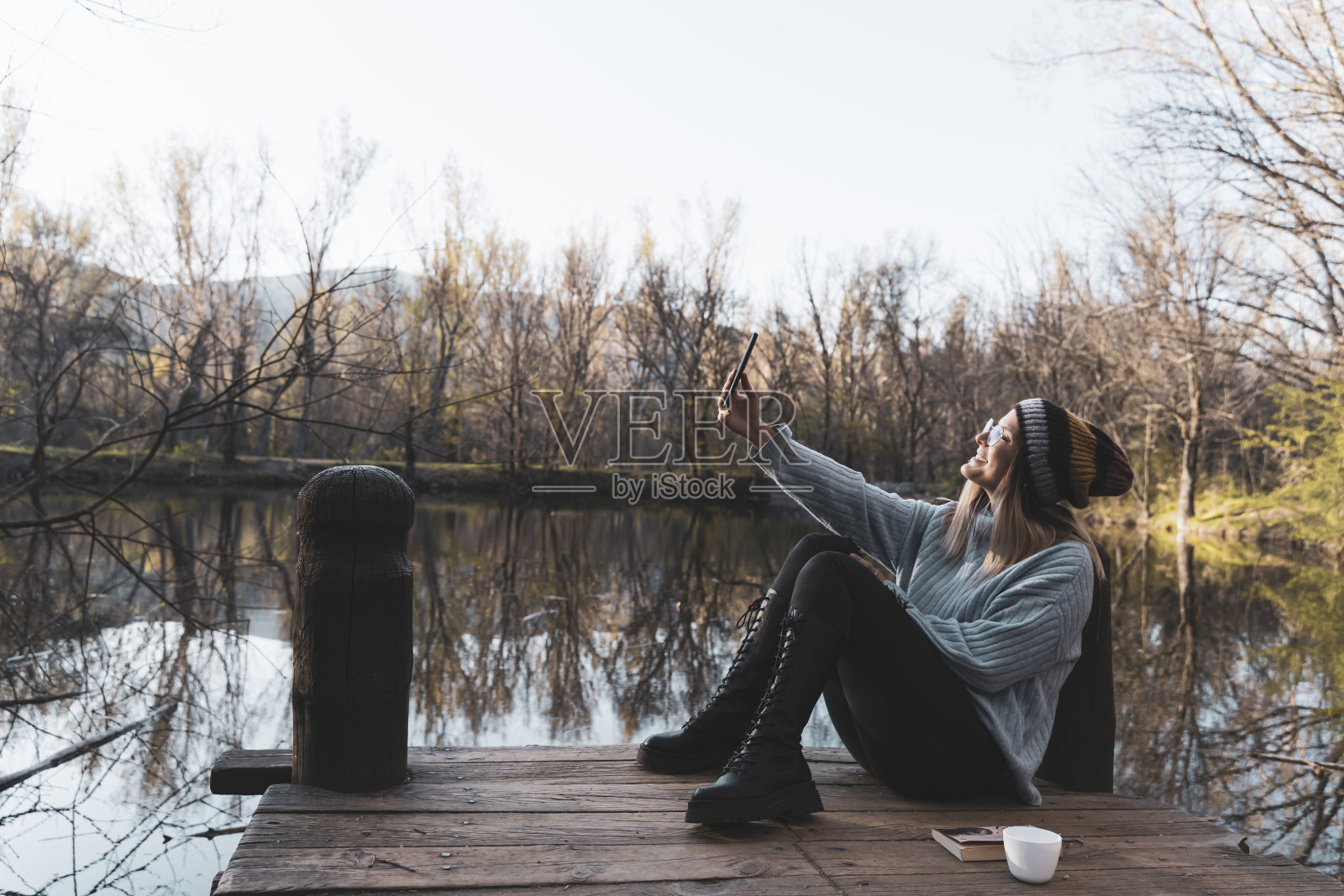 年轻女子在木码头湖放松与智能手机照片摄影图片