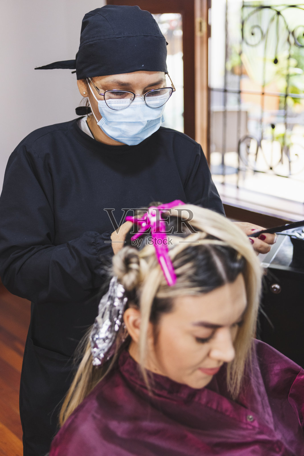 在哥伦比亚的美容院里，一位西班牙理发师正在给一位年轻女子的头发上色照片摄影图片