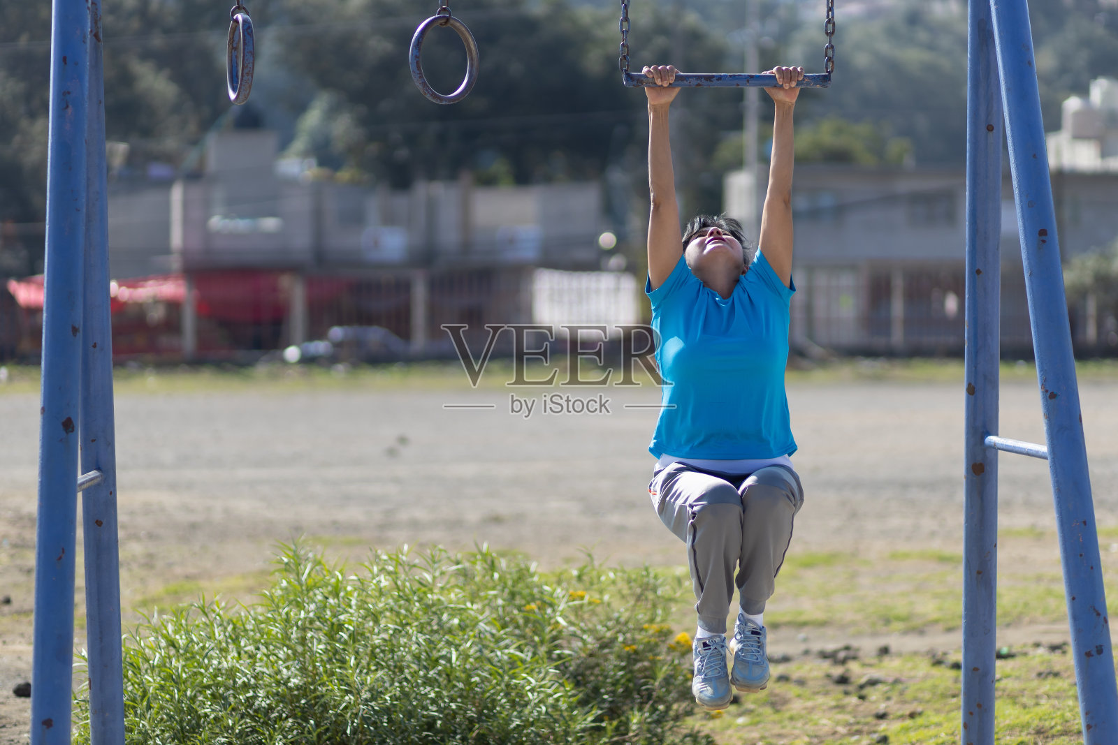 一名墨西哥老妇人在室外金属棒上做俯卧撑照片摄影图片