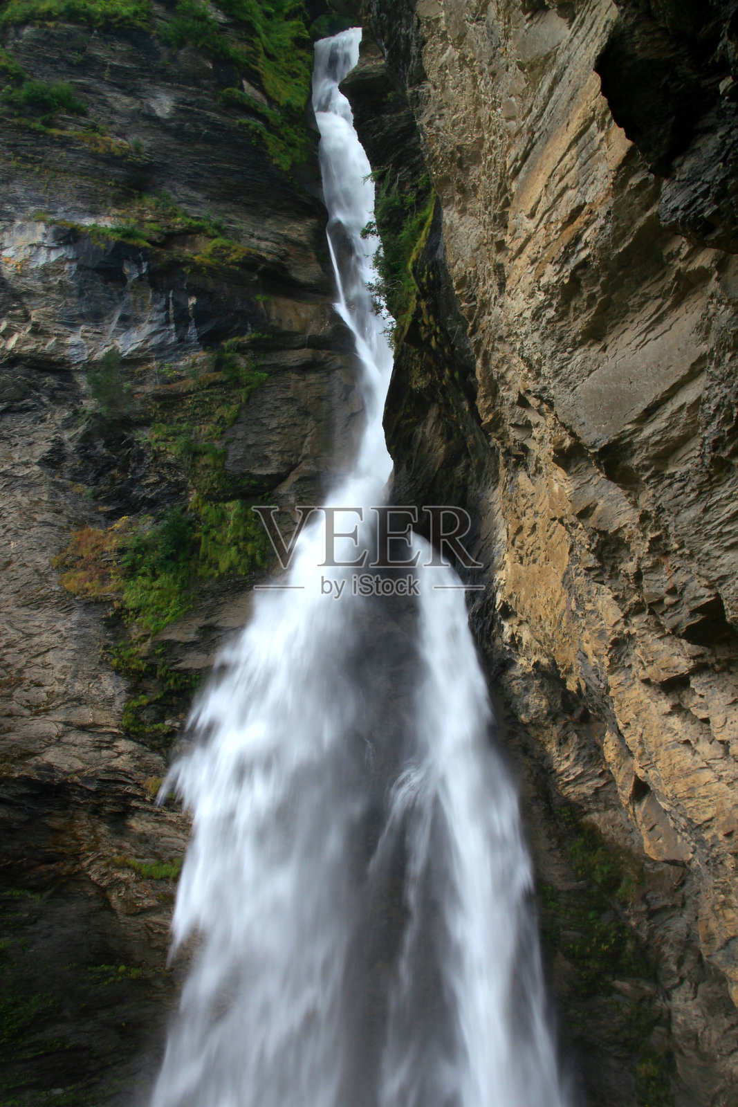 在瑞士迈林根附近，瀑布在石头和灌木丛中快速下落照片摄影图片