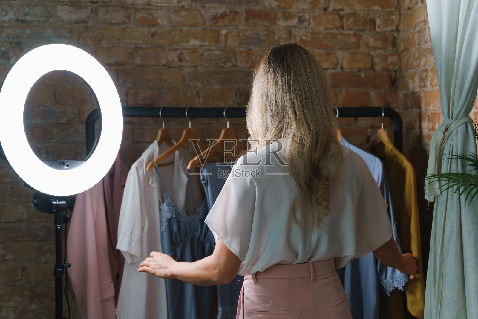 年轻漂亮的女人和衣架与不同的服装照片摄影图片