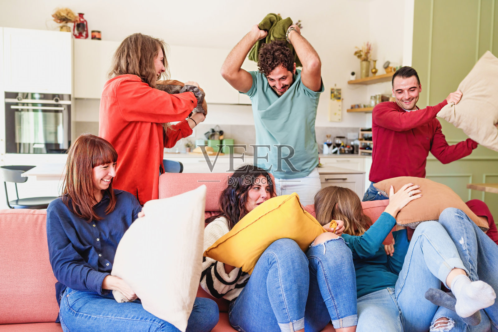 年轻的朋友在客厅举行枕头大战派对照片摄影图片