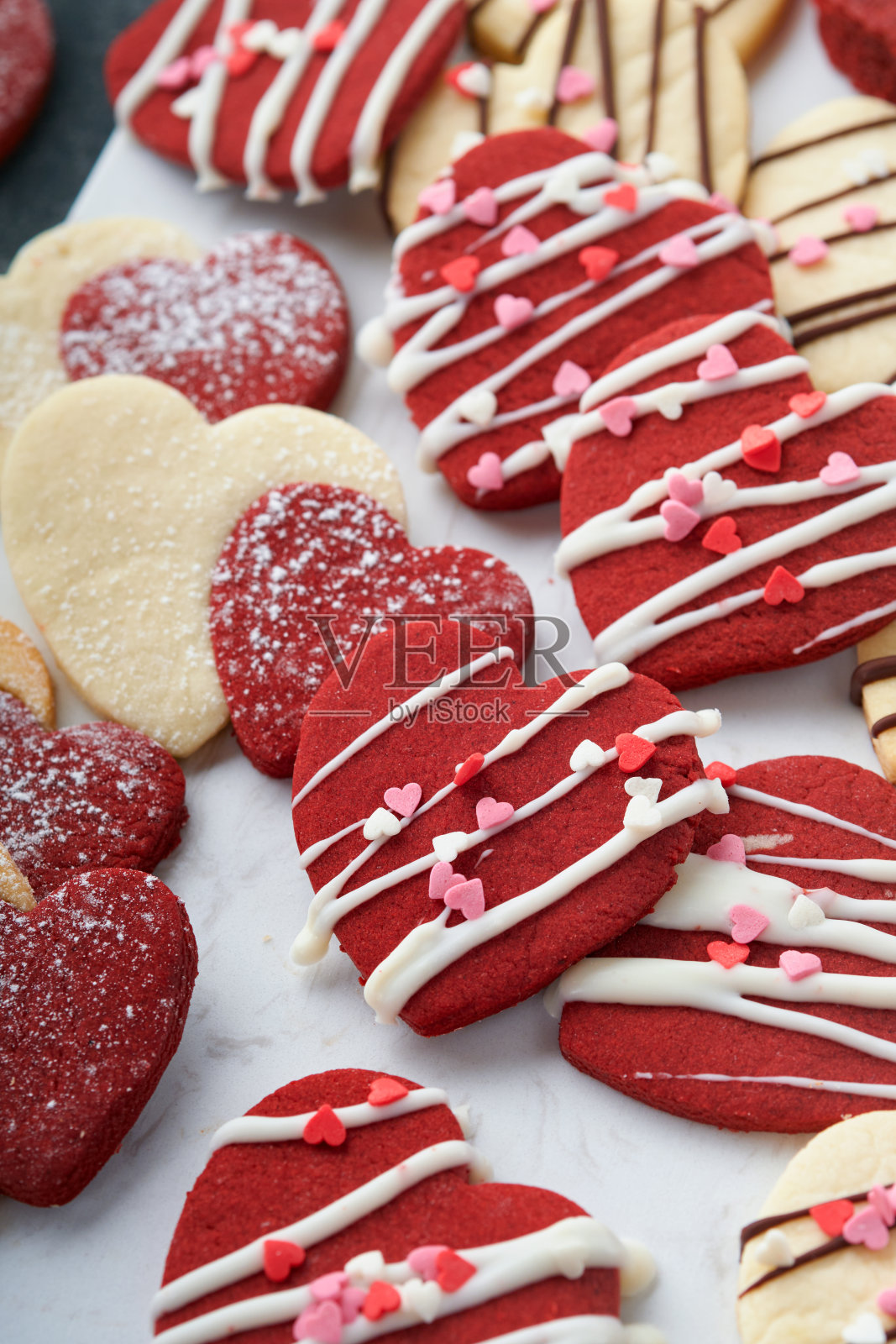 情人节饼干。酥饼内甜红心巧克力釉在粉红盘灰色背景。母亲的一天。女人的一天。甜蜜的节日烘焙。情人节卡片。前视图。照片摄影图片
