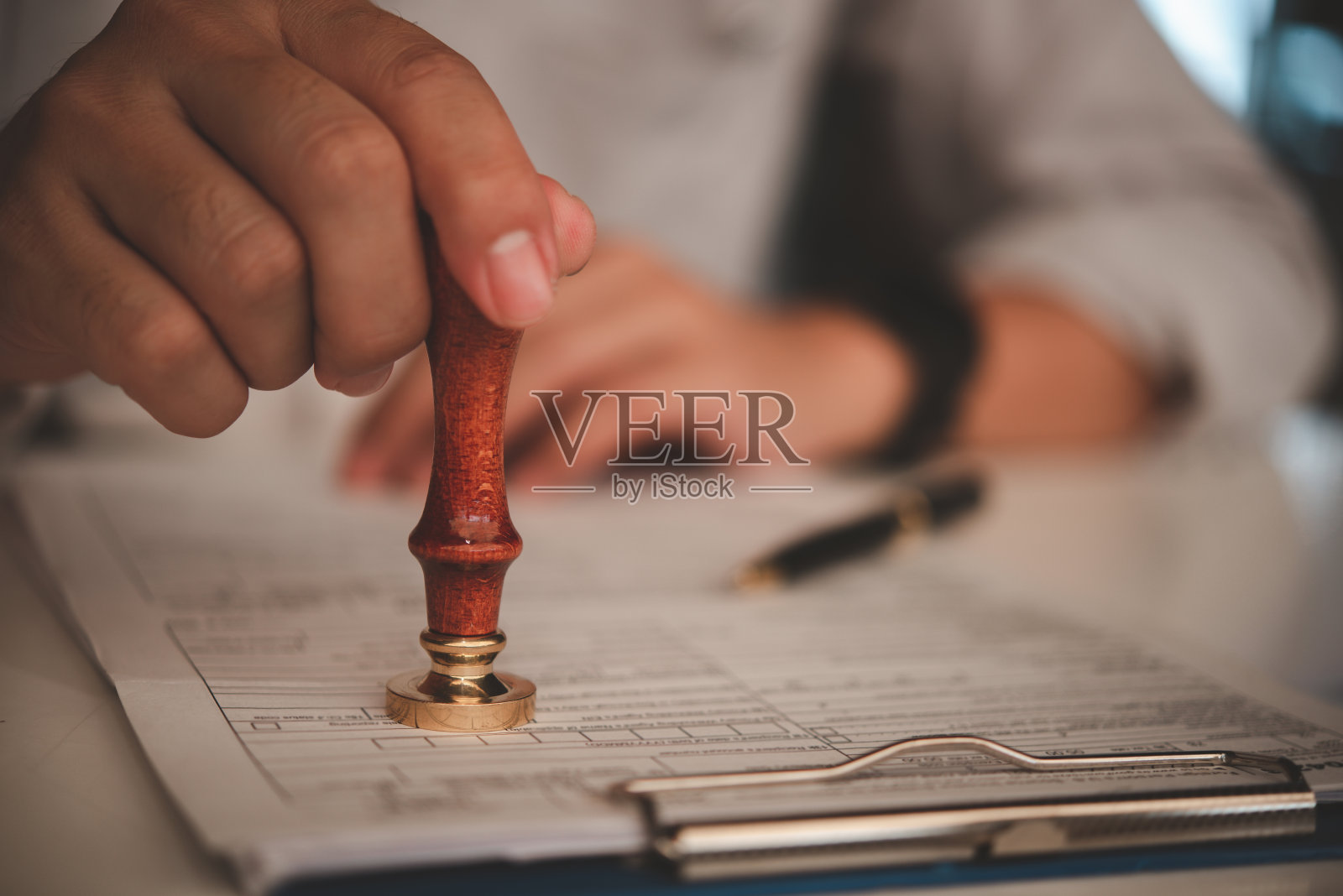 商人在办公室的证书文件合同上盖章批准。律师在木桌上的文件上盖章。照片摄影图片