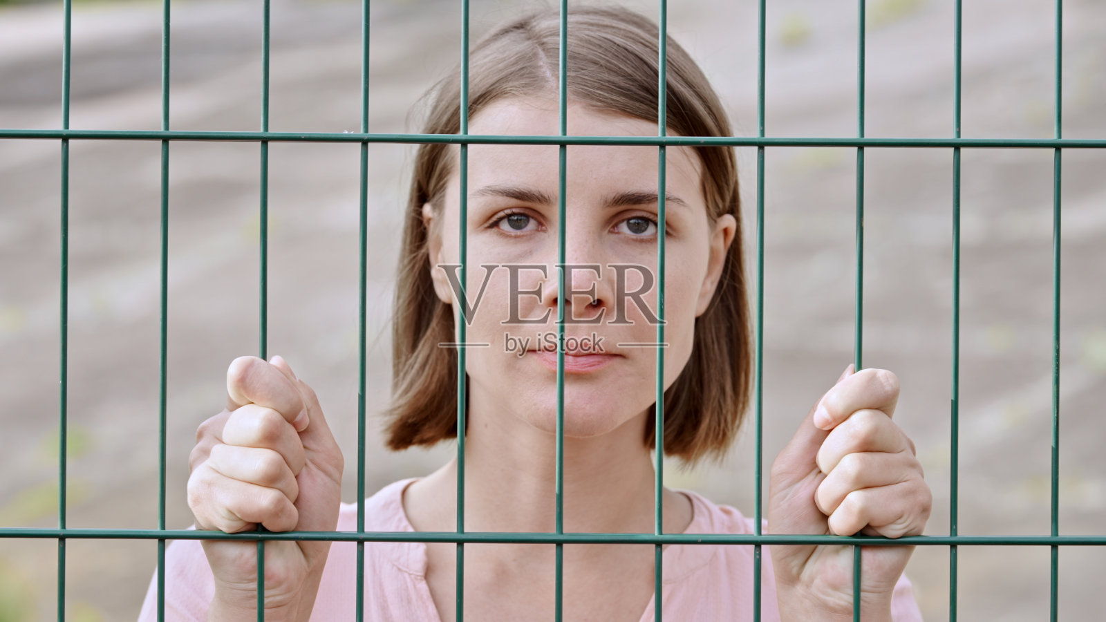 一个白人妇女透过栏杆看向摄像机的特写镜头照片摄影图片