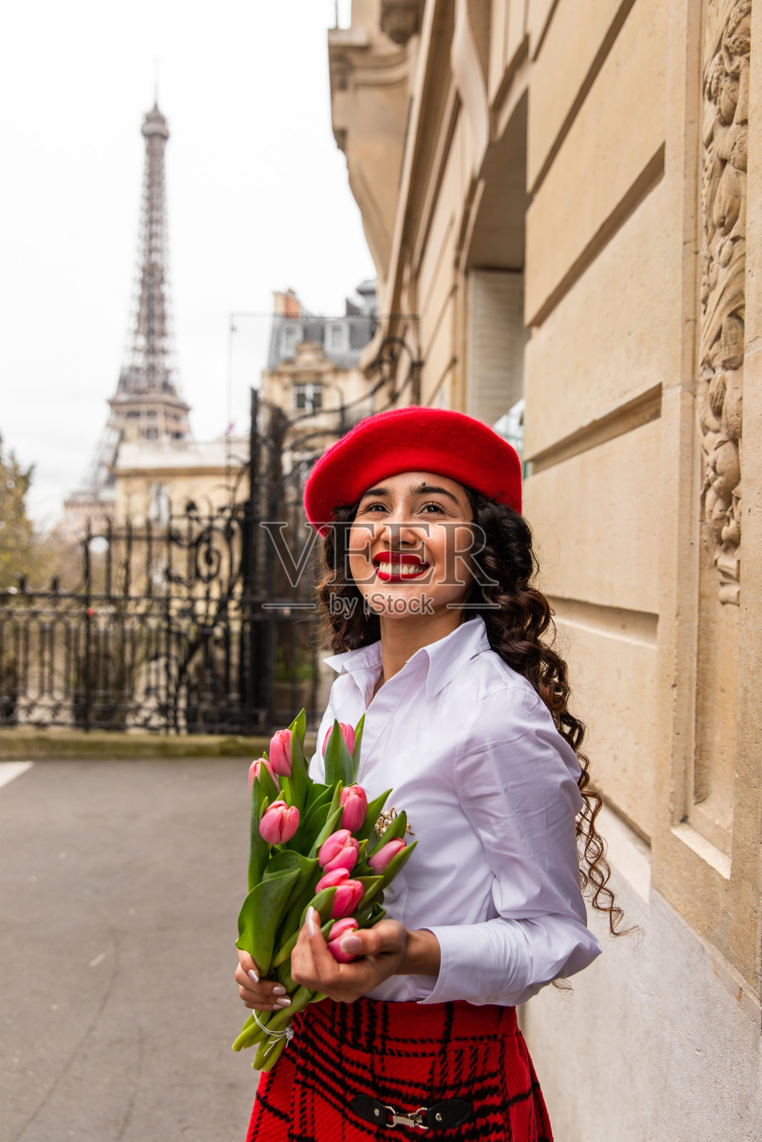 在法国巴黎，一个时髦的女孩拿着一朵郁金香照片摄影图片