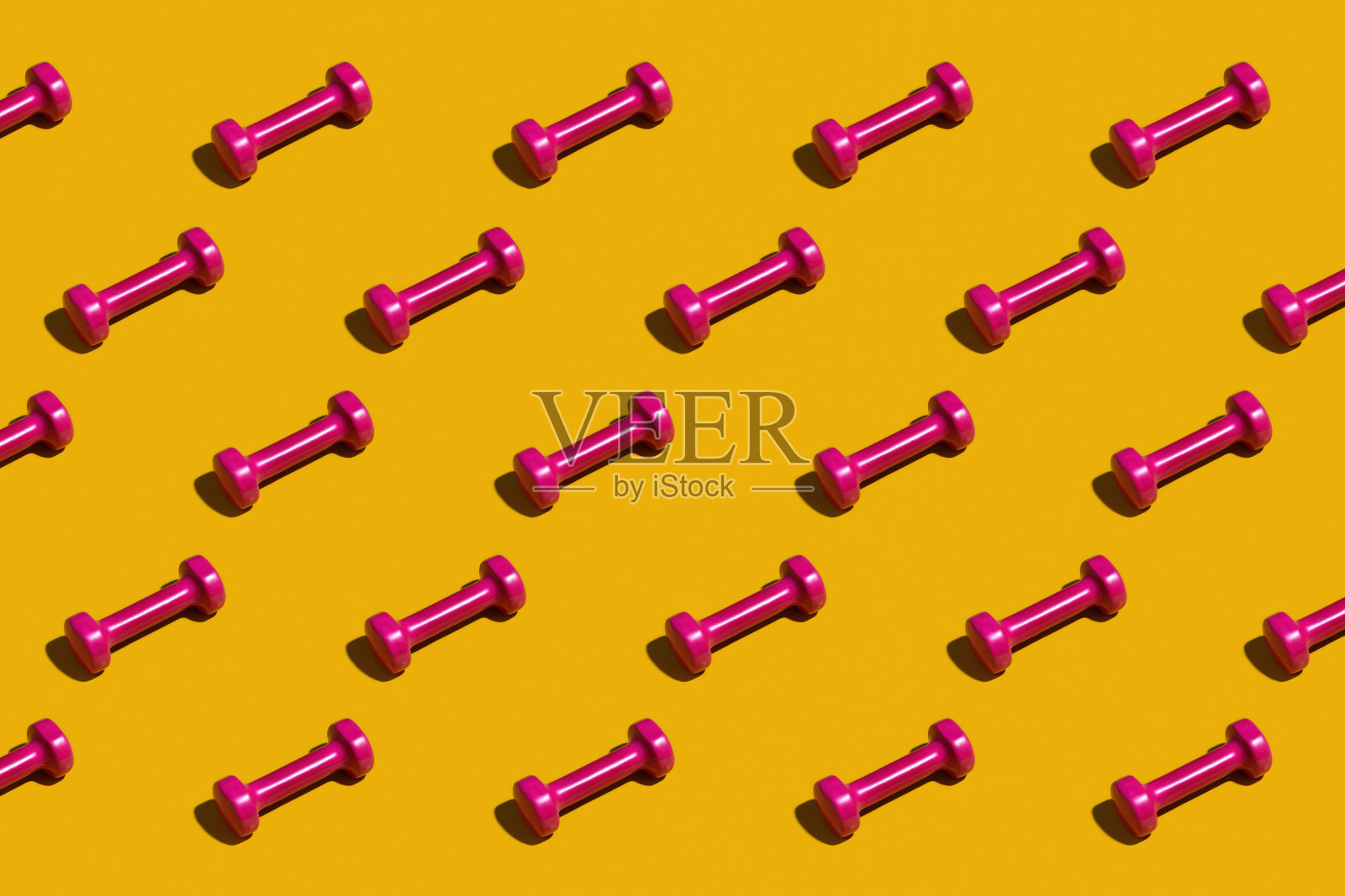 黄色背景上亮粉色的哑铃照片摄影图片