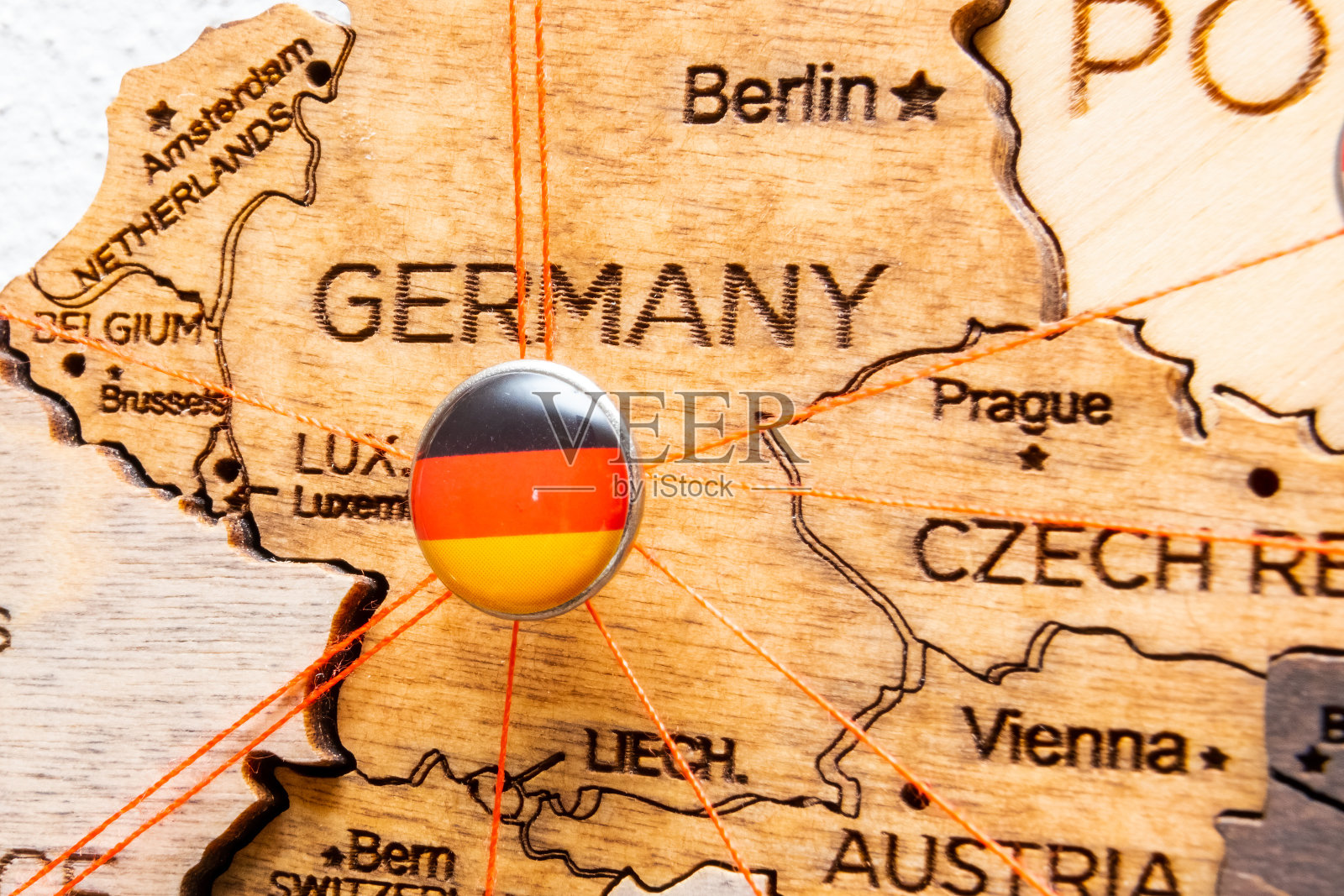带红线的大头针上的德国国旗显示了木制地图上的道路。照片摄影图片