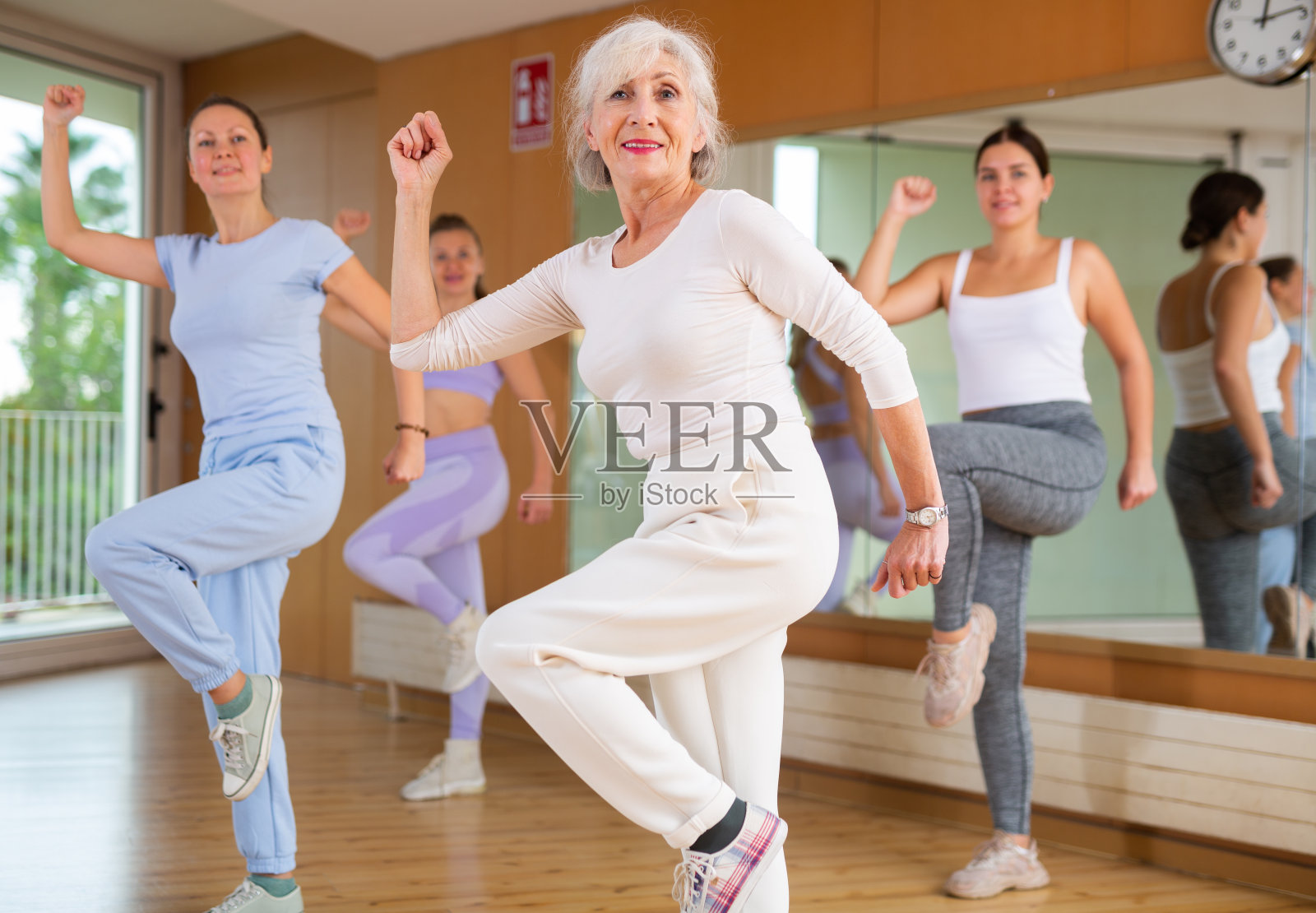 成熟的女教练跳舞和练习新动作与一群年轻的女性在健身房。舞蹈和健康的概念照片摄影图片