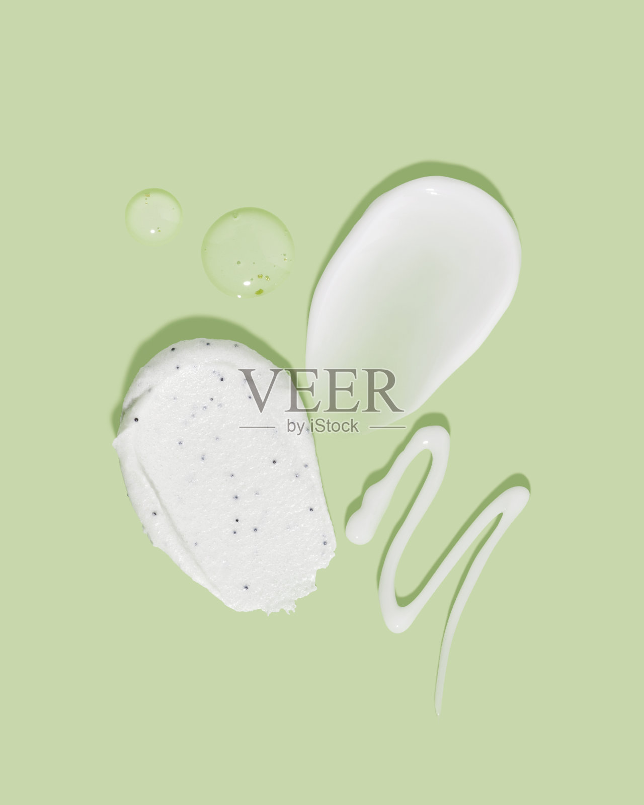 由各种化妆面膜，面霜，精华液和磨砂涂抹在绿色背景。美丽纹理。化妆品样品。照片摄影图片