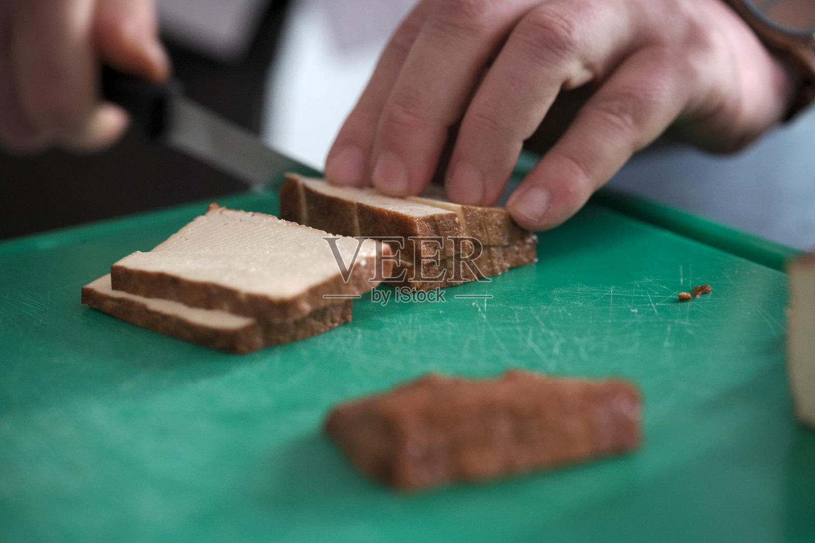 厨师在绿色砧板上切熏豆腐照片摄影图片