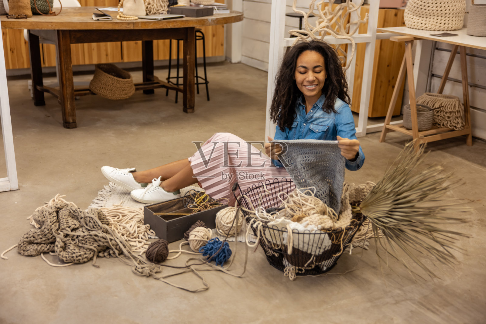 年轻女子坐在地板上，看着流苏工具照片摄影图片