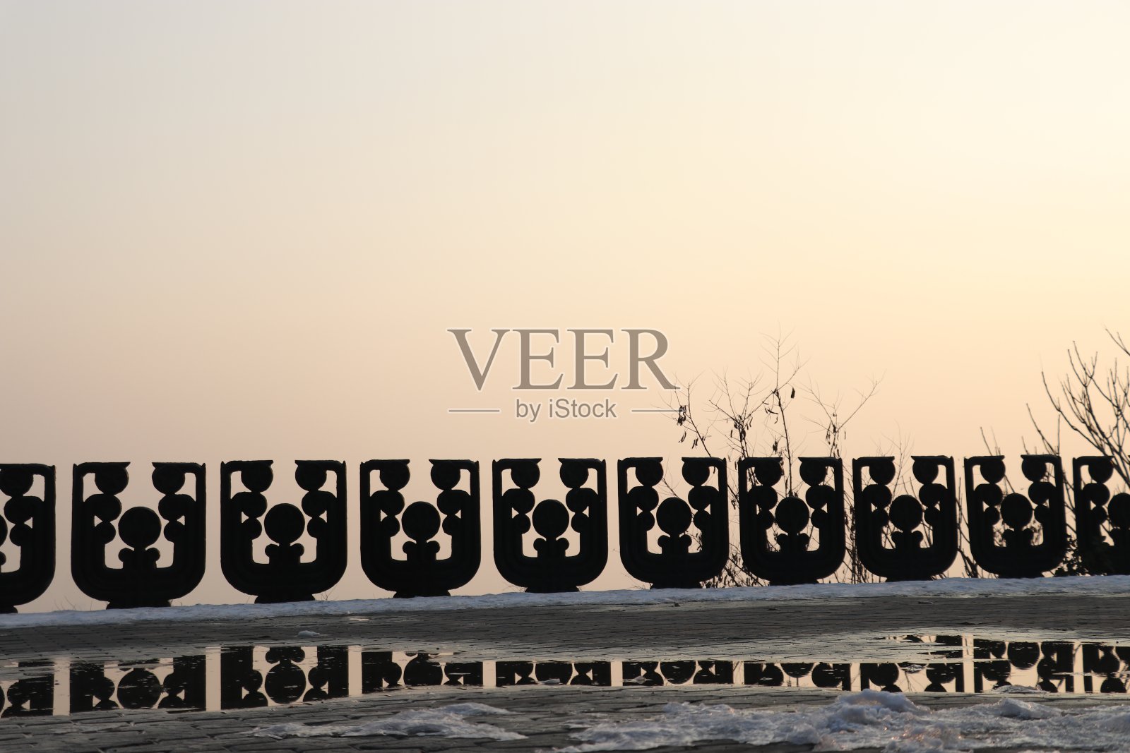 寒冷的冬天，日落时分，大雪纷飞的街道上的石头隔墙照片摄影图片