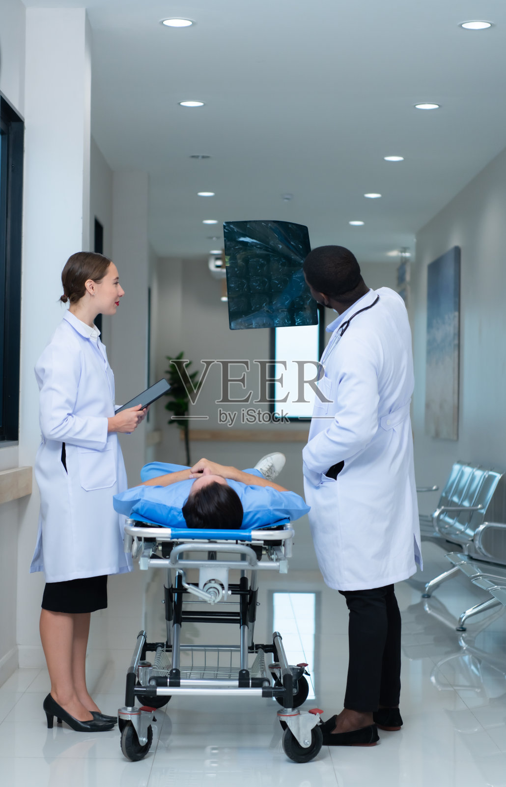 医学老师和实习生在看一名事故后遭受脑震荡的病人的脑部x光结果。告诉病人大脑正常照片摄影图片